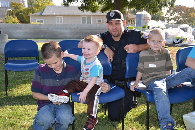 Lucas Van Hoek (the smiling one) gets new shoes as his brother Demitri Van Hoek (left) and brother Gauge Van Hoek, look on. Officer Brett Ward watches as Lucas tries on the new shoes.